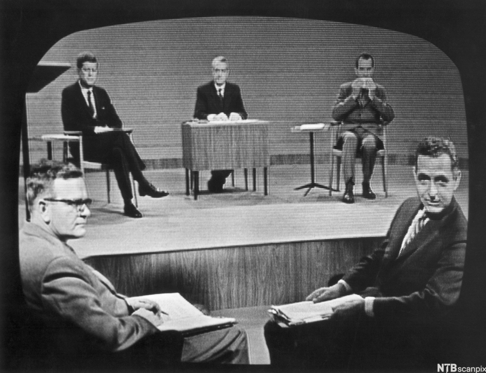 A photo of a television broadcasting the first Kennedy Nixon debate with the moderators in the foreground and on the stage