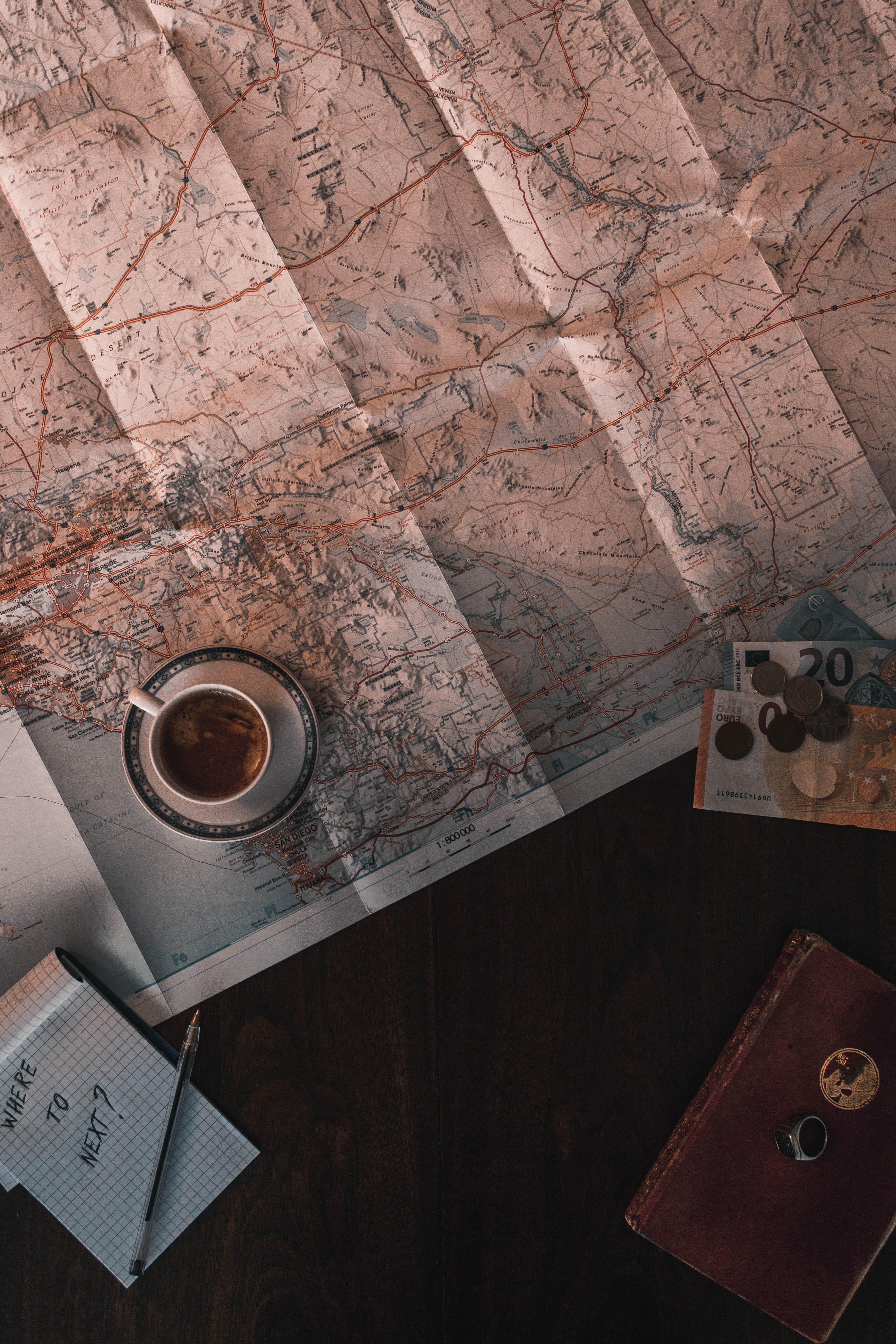 Image of a cup of tea sitting in the corner of a map spread out on a table