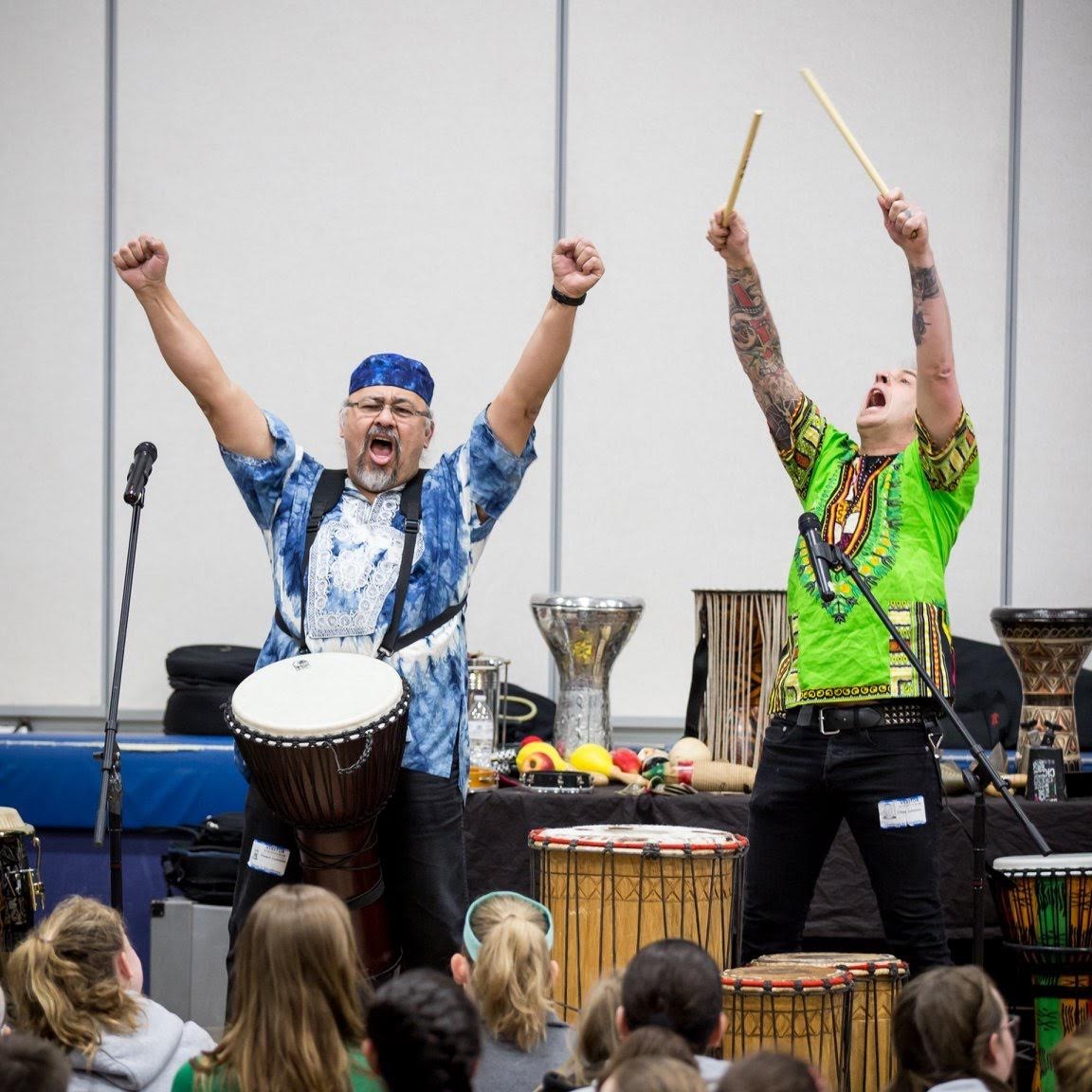 Drummers with their arms raised holding drum sticks