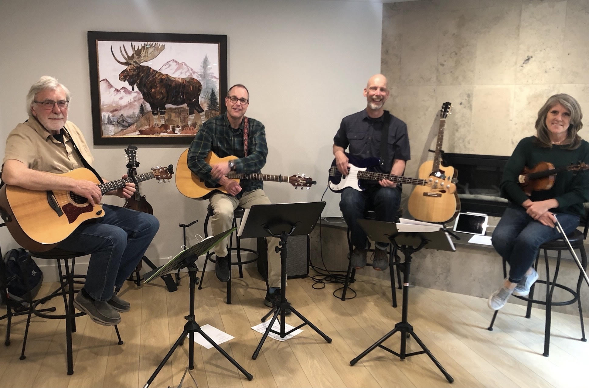 The Lost Creek String Band poses in front of a painting of a Moose.