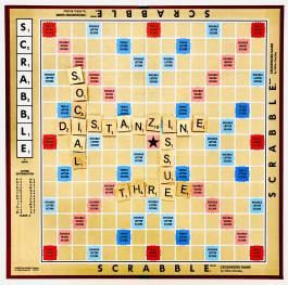 Scrabble board with pieces that spell out "social distanzine issue three"