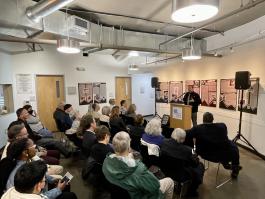 Photograph of awards event. David speaking at podium in front of a packed audience at The Center on Colfax. 