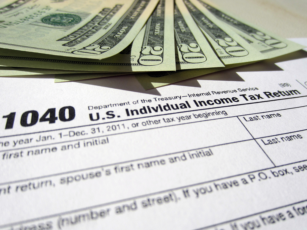 Twenty-dollar bills spread out over a U.S. 1040 tax form.