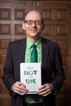 Dr. Greger holding his book How Not To Die