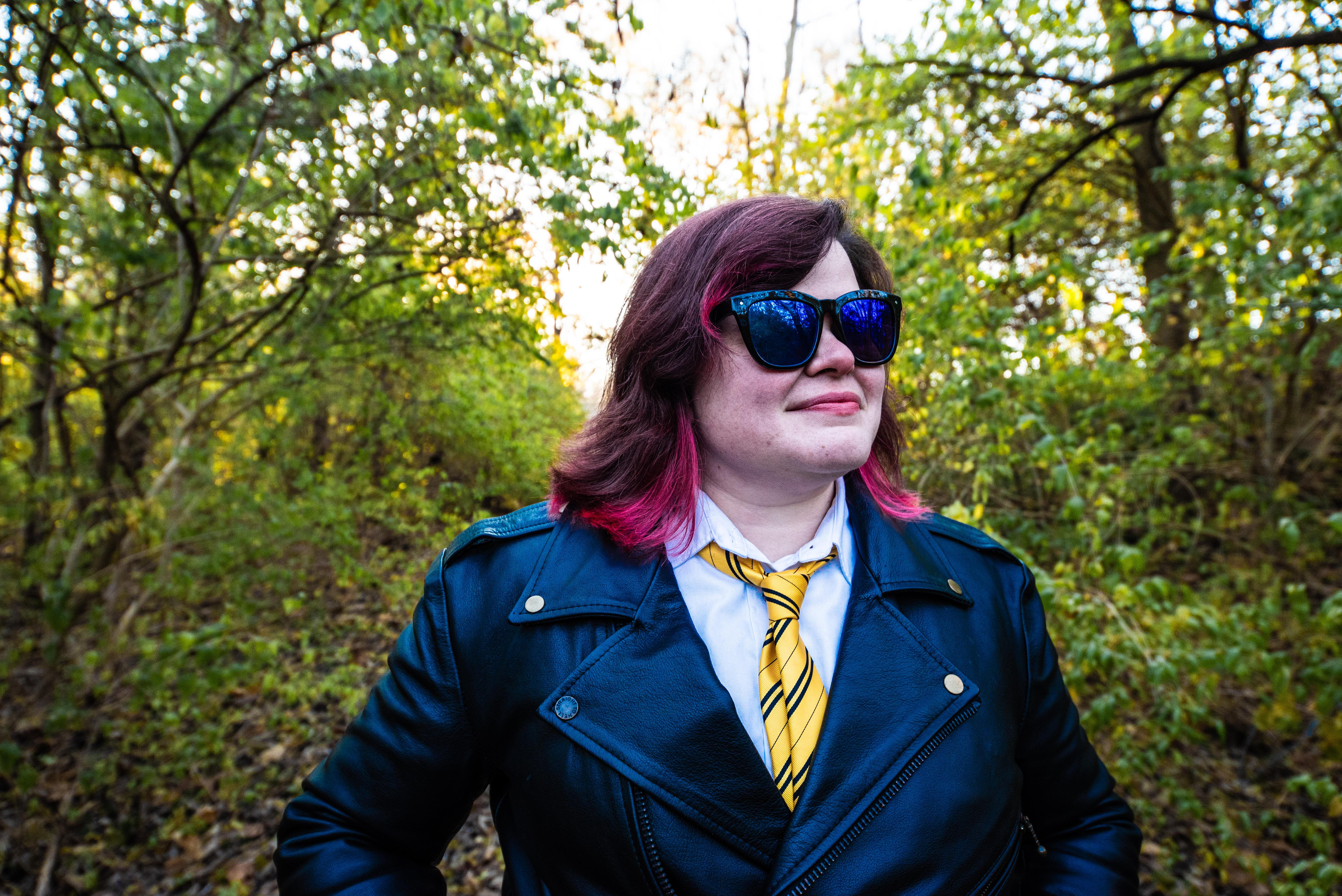 Tonks stands proudly wearing a pair of black sunglasses with lush forest behind her
