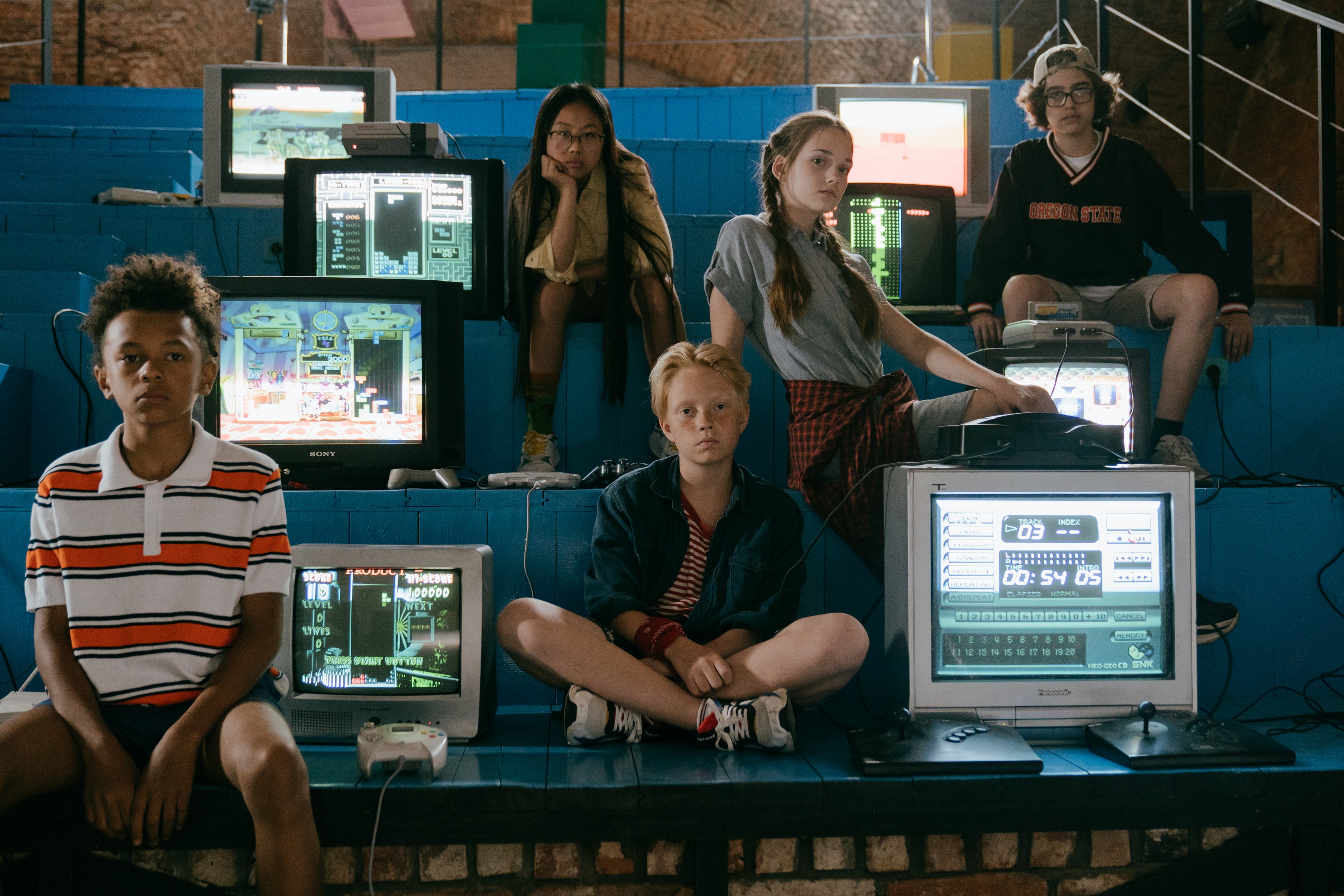 group of teens sitting next to several computers.
