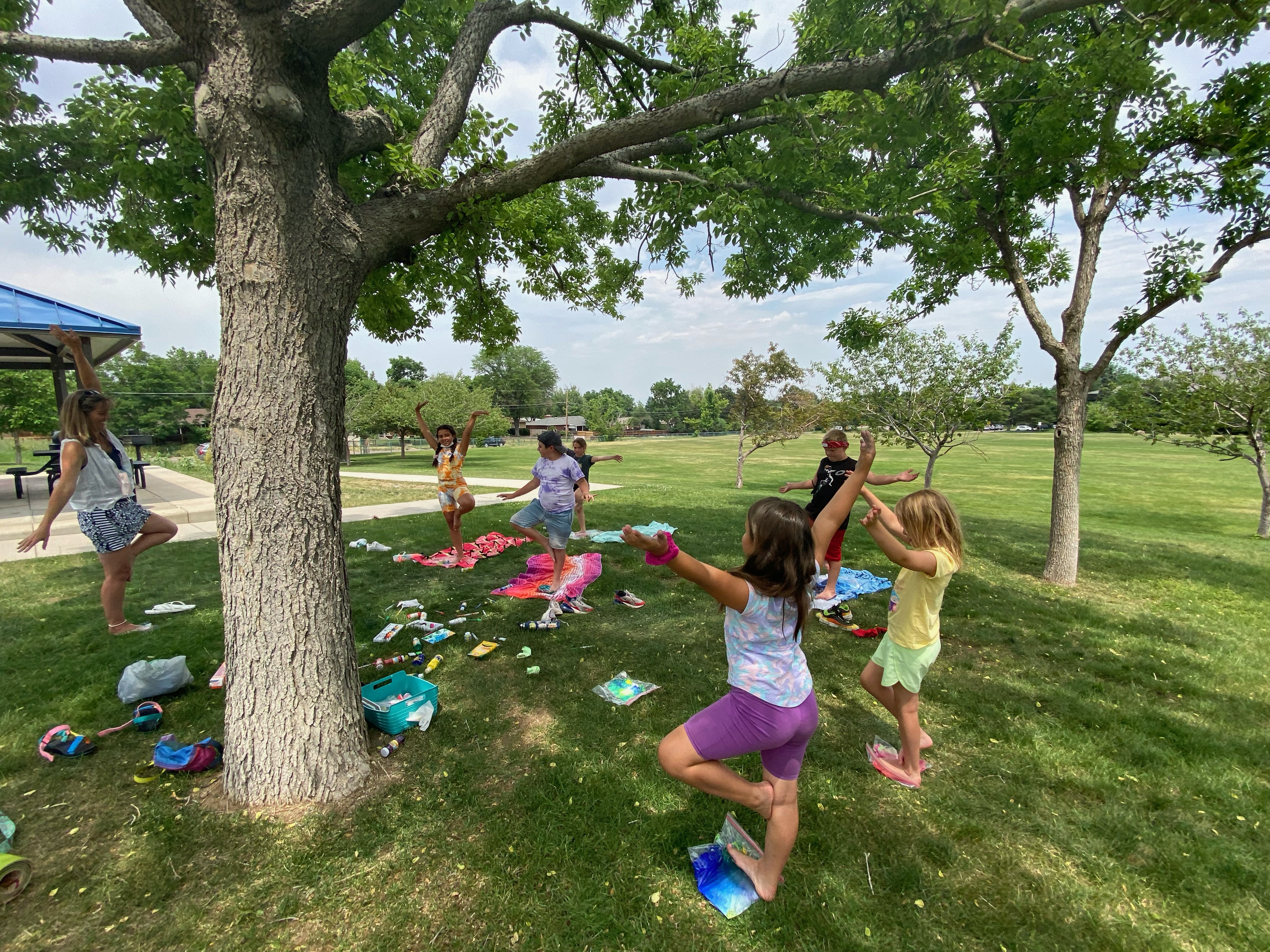 Kids doing yoga outdoors under a tree