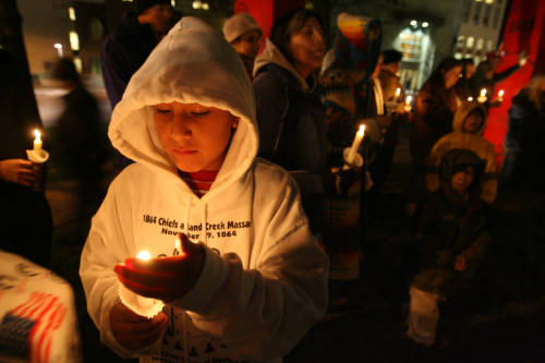 Chris Little Son, 11 of Lame Deer, MT., shields his candle, Friday Nov. 24, 2006 during a vigil of Sand Creek Massacre at the Denver Art Museum 'Wheel' Sculpture.