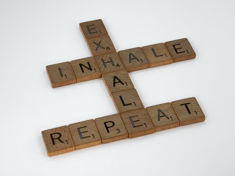 Scrabble tiles arranged to spell "INHALE" "EXHALE" "BREATHE"