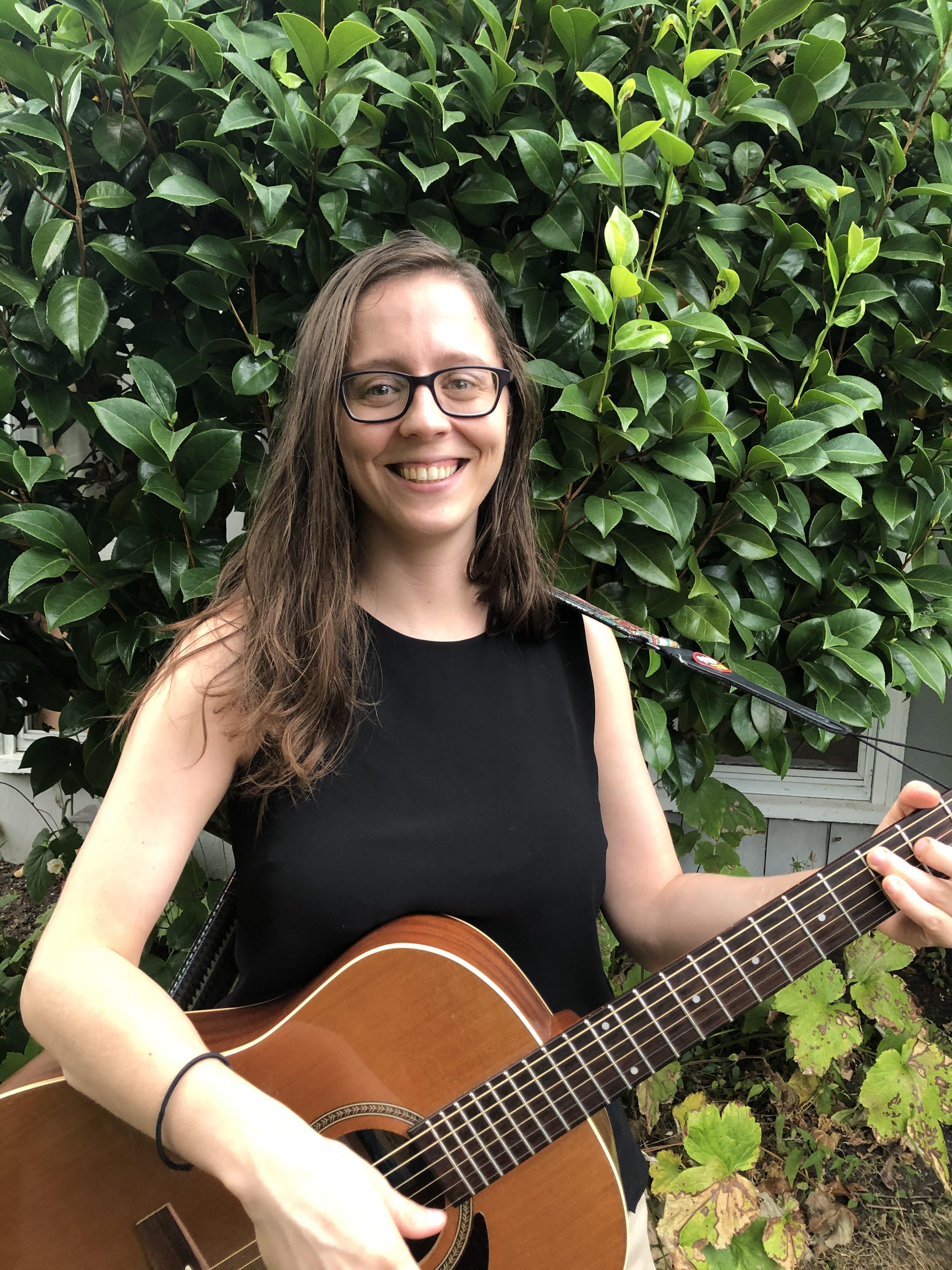 Woman holding a guitar and smiling 