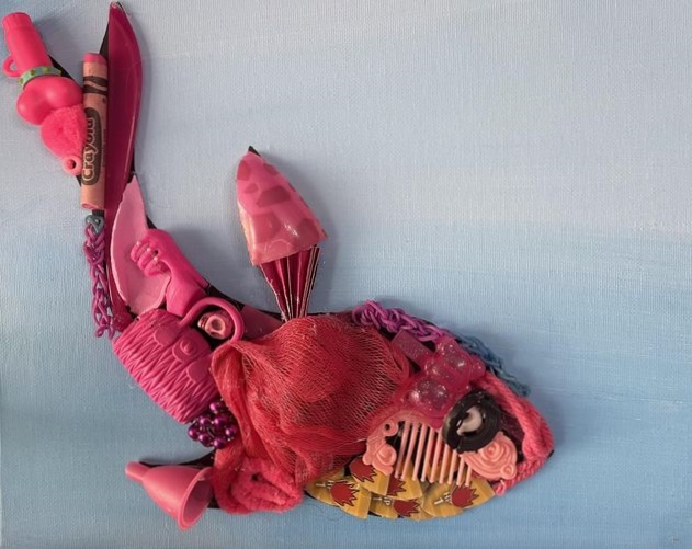 a pink fish made out of trash on a blue canvas