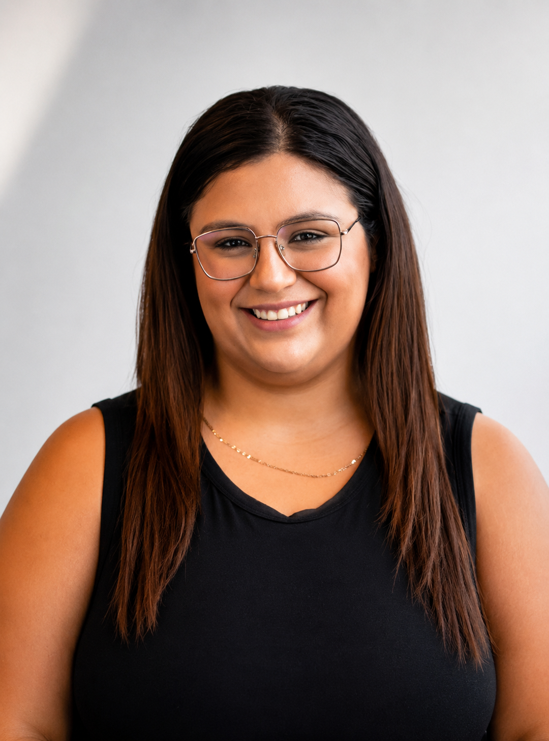 Andrea smiling with square glasses and a white back drop.