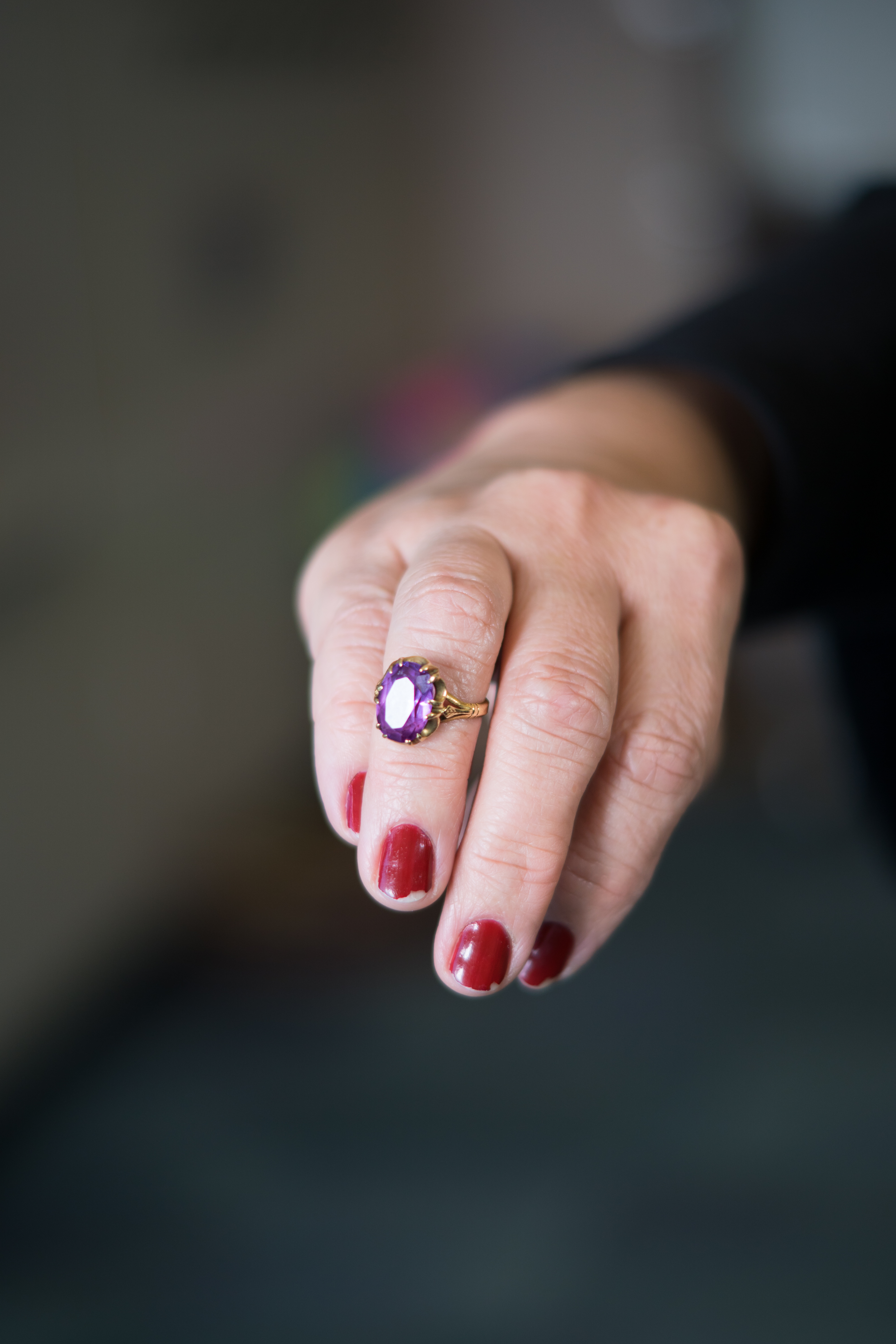 Hand holding a ring with a purple gemstone.