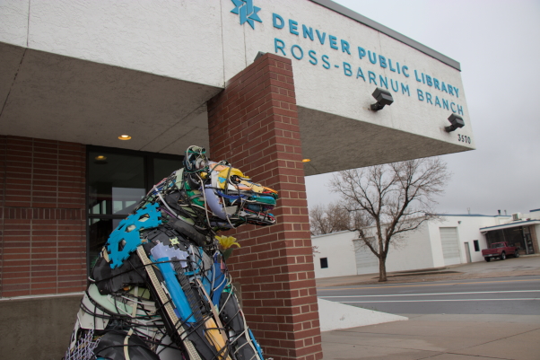 A picture of the Ross-Barnum Branch Library building that shows the library name. You can also see a structure in the form of a bear that is created from recycled materials. It sits in front of the library building.