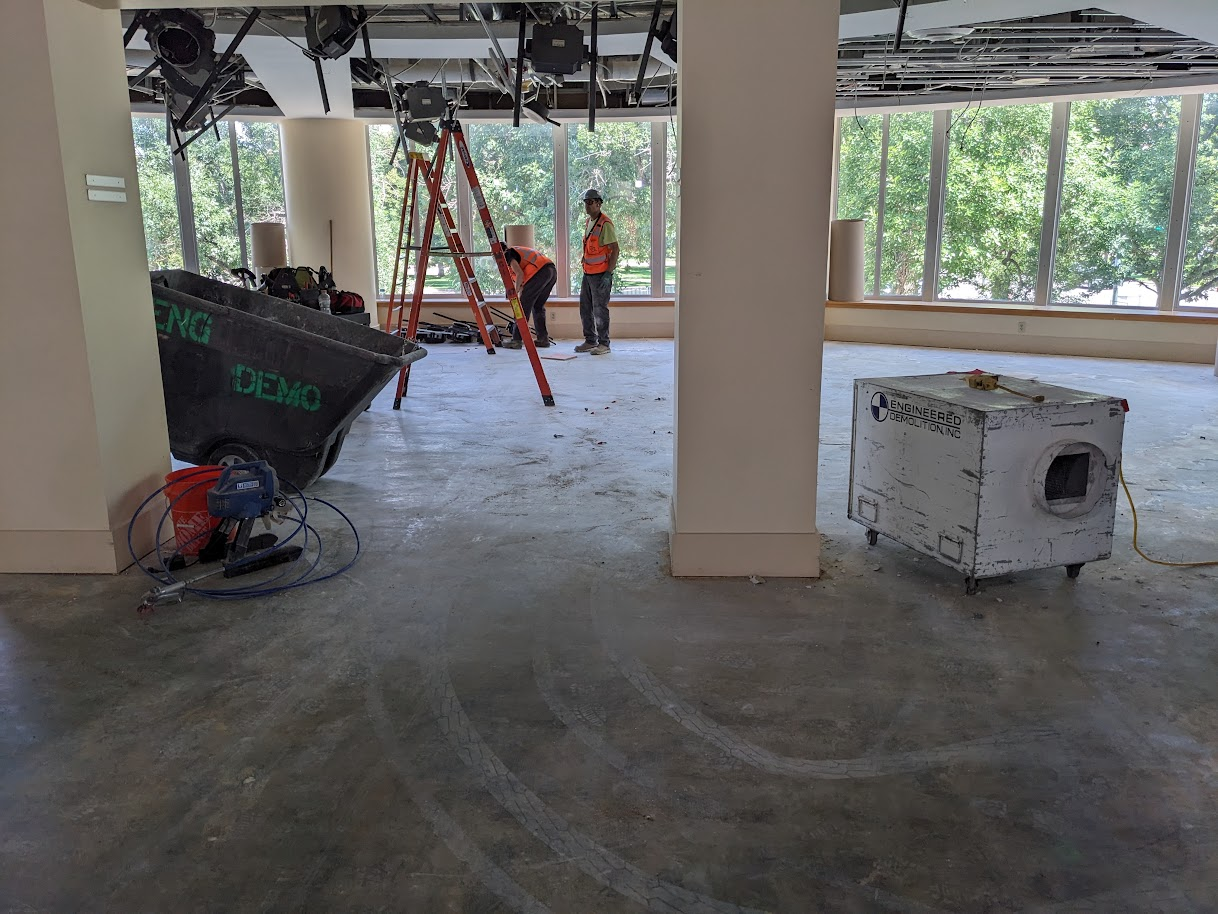 Renovation work begins for a new teen library space. The same area from the previous photo shows no carpet and no book shelves. Just grey concrete.