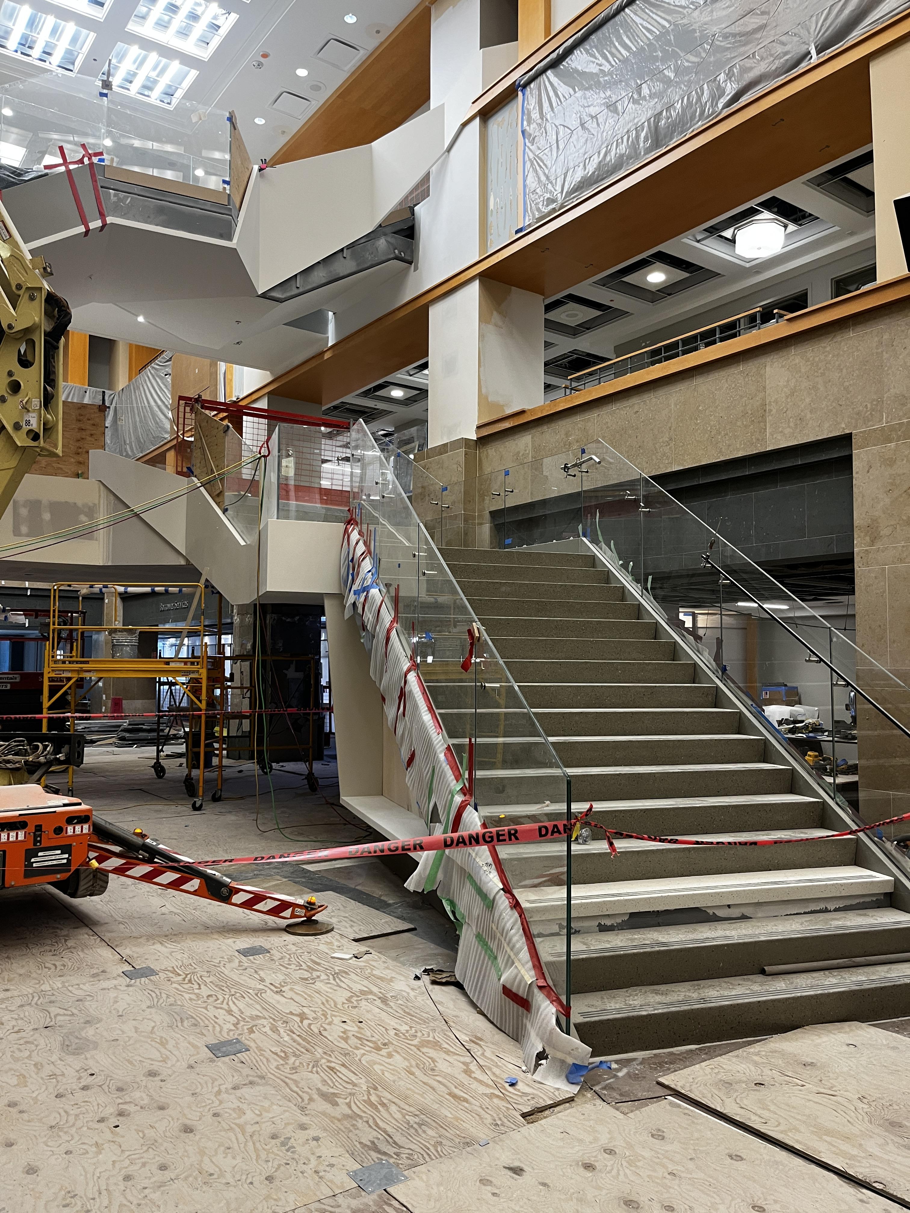 A picture of the newly added grand staircase at the Central Library. The staircase is nearly complete, but the photo shows construction tape and tools surrounding it.