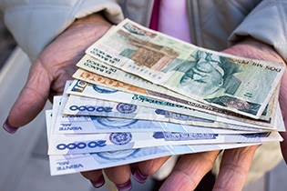 Photograph of a woman's hands holding paper money from Mexico