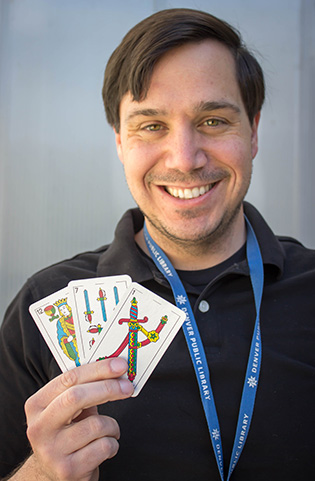 Photograph of a smiling man holding playing cards