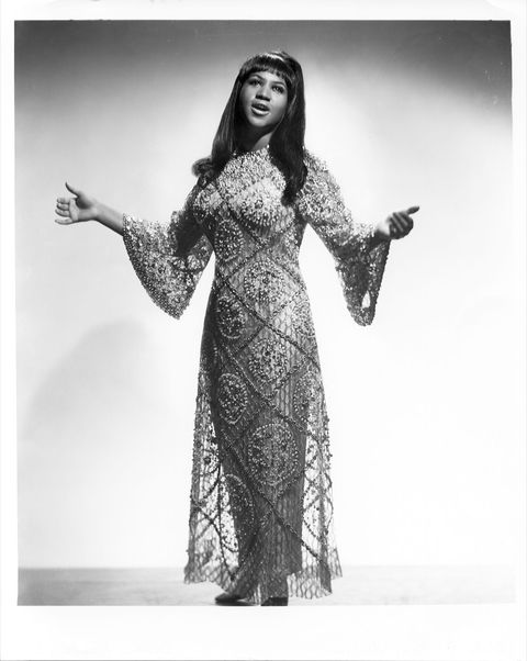 Black and white portrait of Aretha Franklin in a dress with her open gently stretched open
