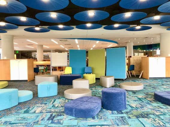 A picture of the new Children's Library. There is colorful, children sized furniture and fun, blue ceiling light lights