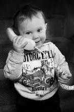 Young child holds a telephone and smiles