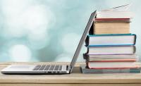 Photo of a laptop next to a stack of books