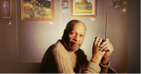 Photograph portrait of Bob Raglan sitting among his art work. 