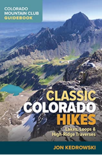 The cover of the book Classic Colorado Hikes. Book title over a photo taken on top of a peak looking down onto a mountain lake.