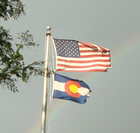 U.S. and Colorado flags flutter from the same flagpole. Denver Library image