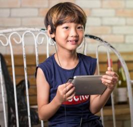 Child on a chair using a mobile device with headphones