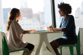 Two women facing each other at a table. Photo by Christina @ wocintechchat.com on Unsplash.