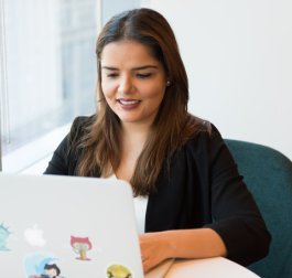 Woman smiling as she looks at a laptop