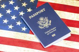 A blue American passport on top of the American flag.