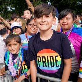 A smiling child wearing a Pride tshirt