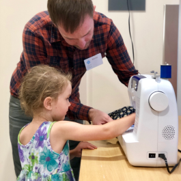 librarian helping child sew