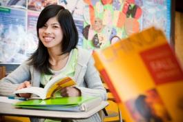 Woman at a desk with a book open and smiling