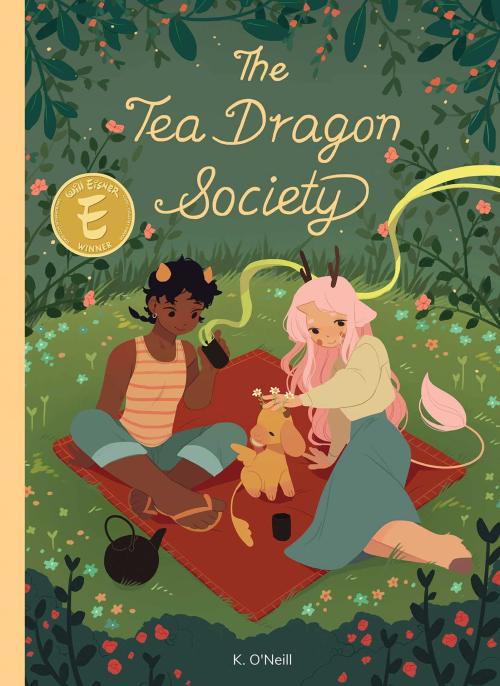 Tea Dragon Society book cover with two people with horns lounging on a blanket with a baby dragon