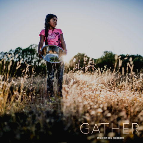 A young native girl looks off into the distance, holding a bowl filled with foraged food.