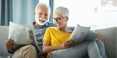 Mature couple reading newspaper and magazines