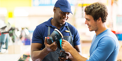 Hardware store worker showing customer a sander