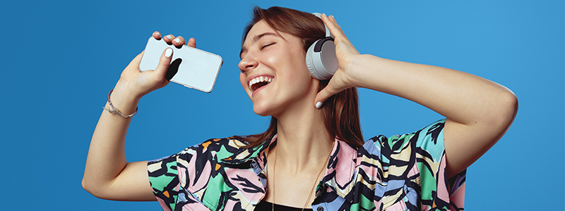 Young girl with wireless headphones singing and dancing