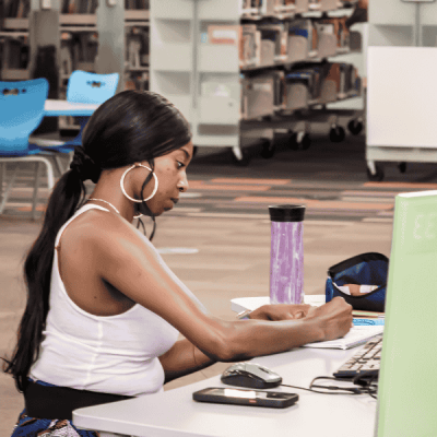 brown skin woman with long dark hair writing in front of a computer