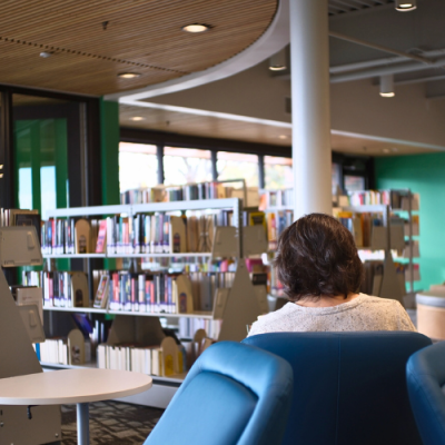 A customer reading a book and seated inside the new Lena Archuleta Branch Library