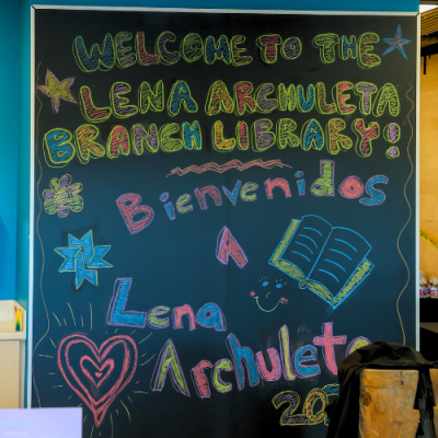 A chalkboard in the Lena Archuleta Branch Library featuring the text, "Welcome to the Lena Archuleta Branch Library - Bienvenidos a Lena Archuleta" 