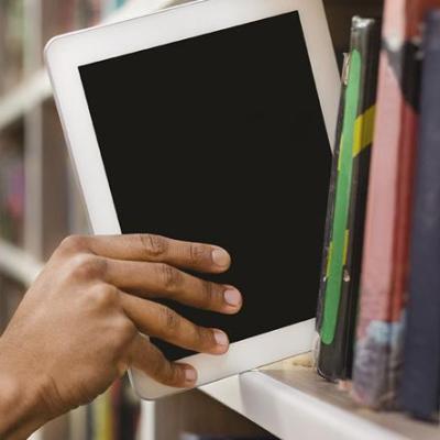 hand putting e-reader on bookshself